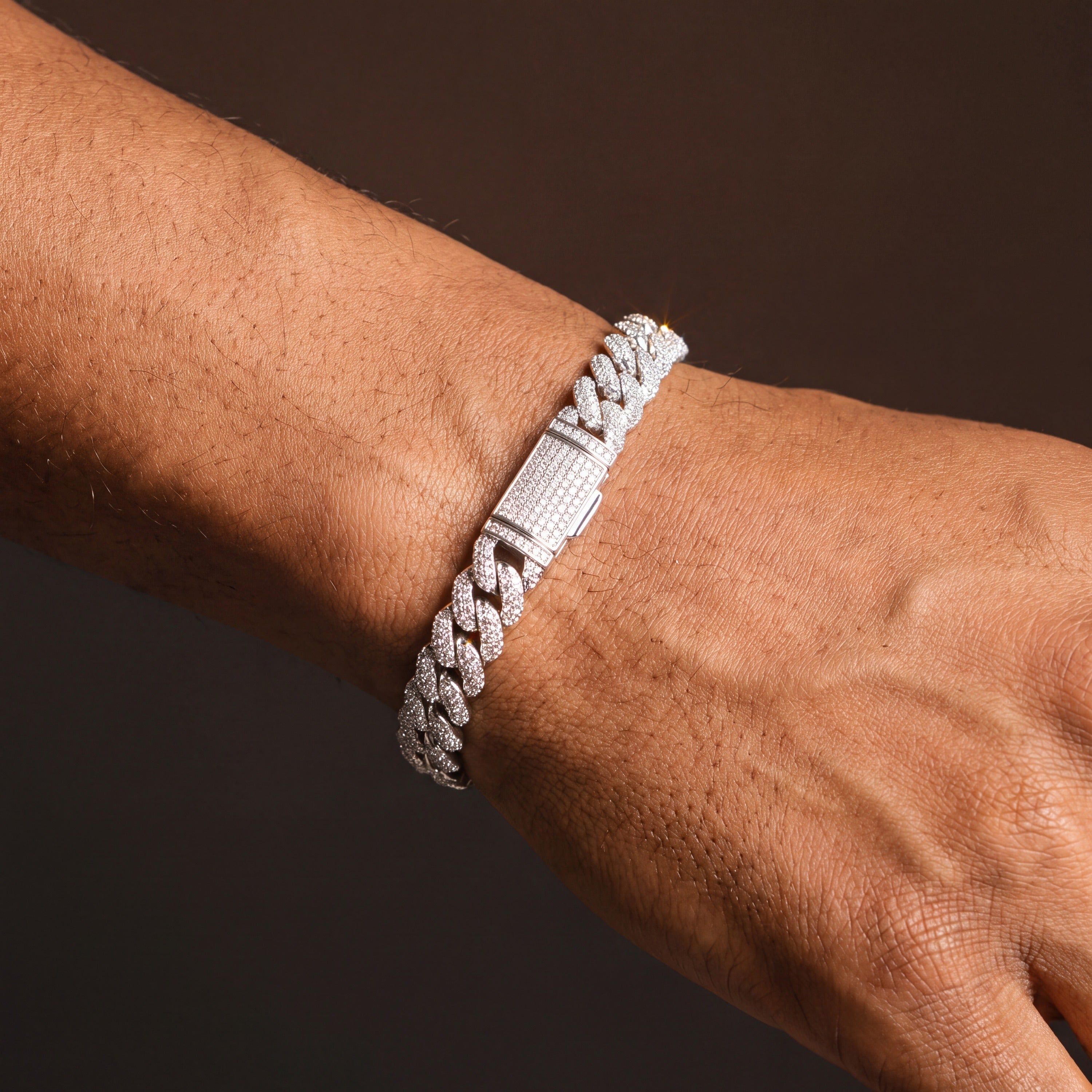 Iced out Cuban link bracelet seen along the wrist, showing the compact pave box clasp